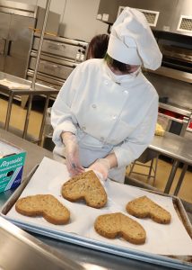 person in kitchen making heart shaped cookies